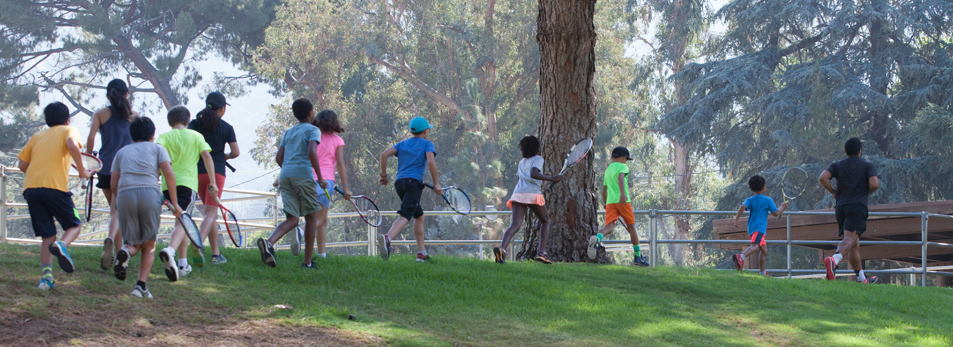 Kids running with coach summer tennis camp